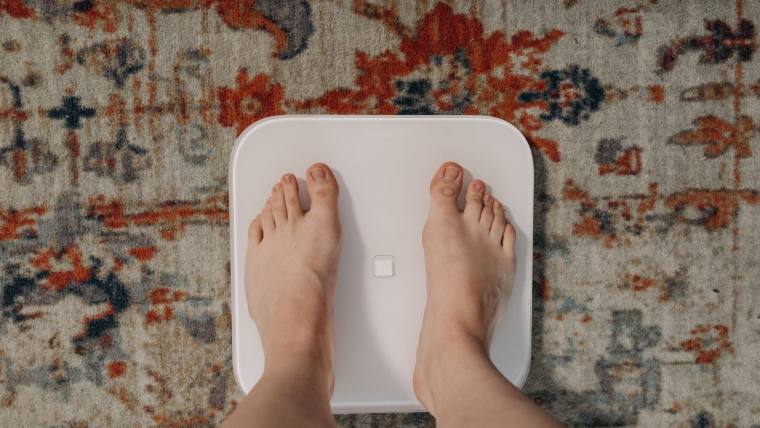 Checking weight on a scale — diabetes, weight and digestive health checks for adults